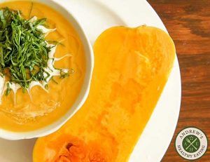 Creamy orange soup with fresh herbs and toasted bread